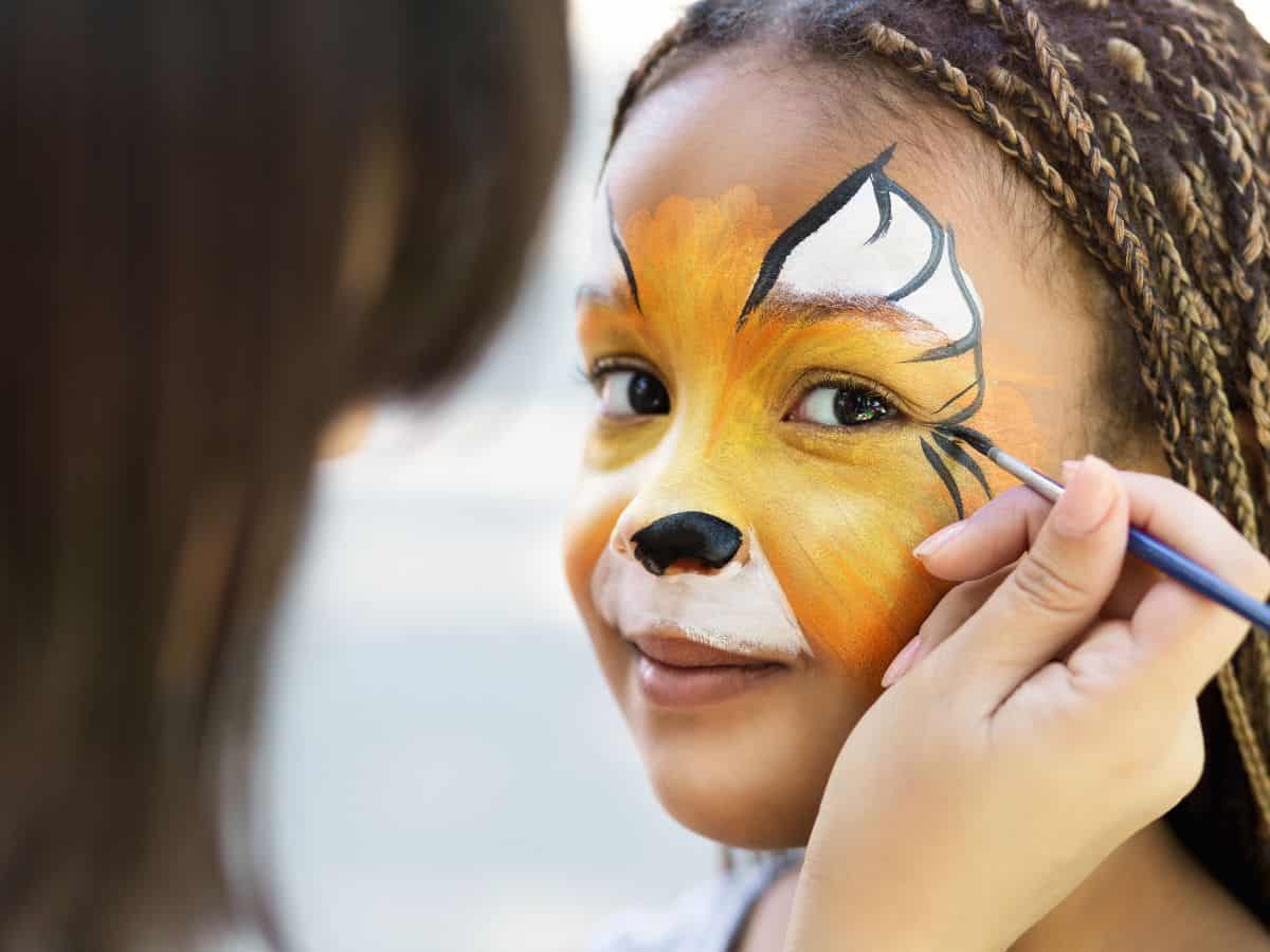 Child having her face painted like a tiger.