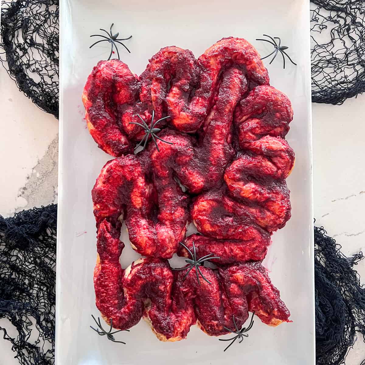 Spooky gruesome intestines appetizer on plate with fake spiders.