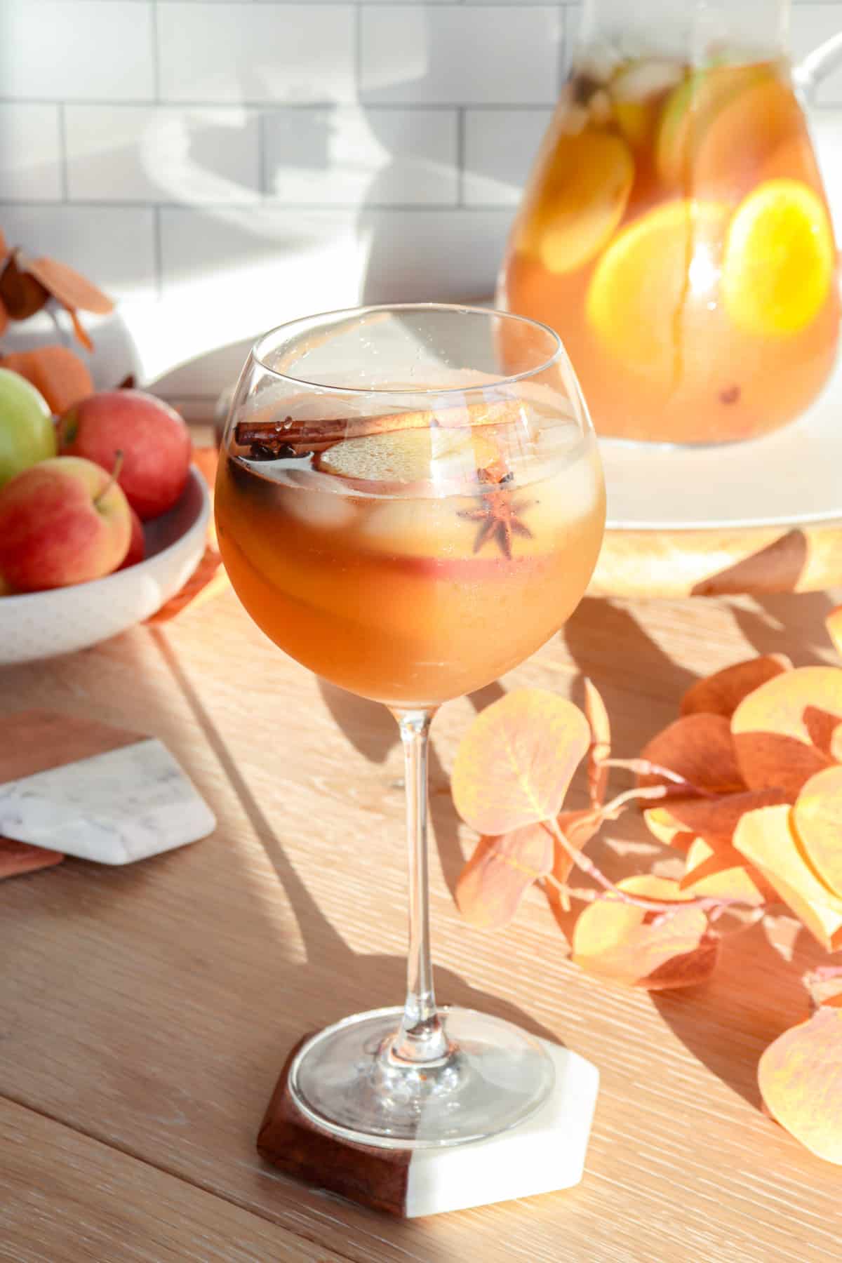 Glass of apple cider sangria with cinnamon and apples.