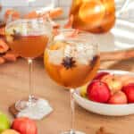 Apple cider sangria in a wine goblet with star anise and apples.