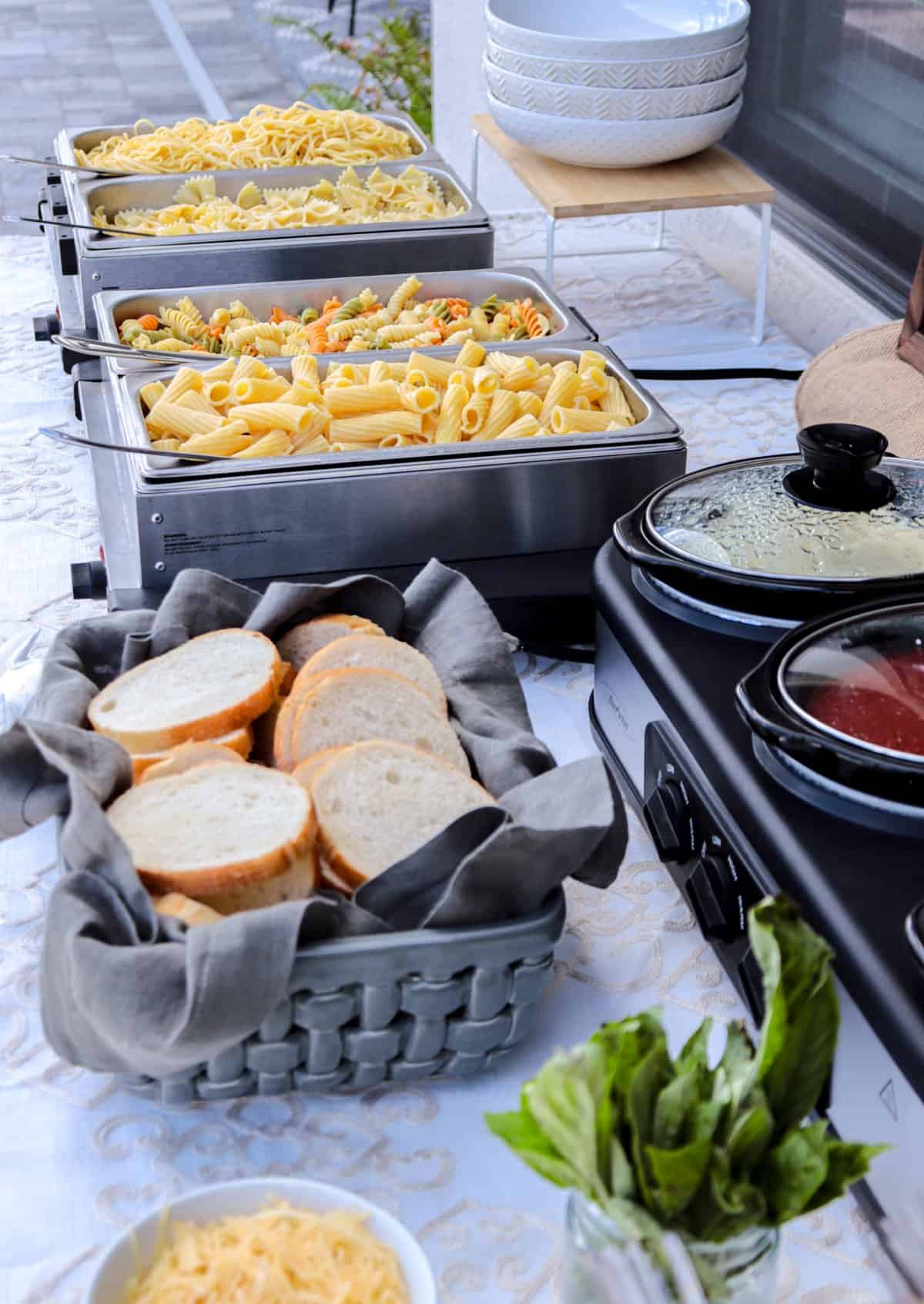 Pasta bar buffet table with pasta, bread and sauces.