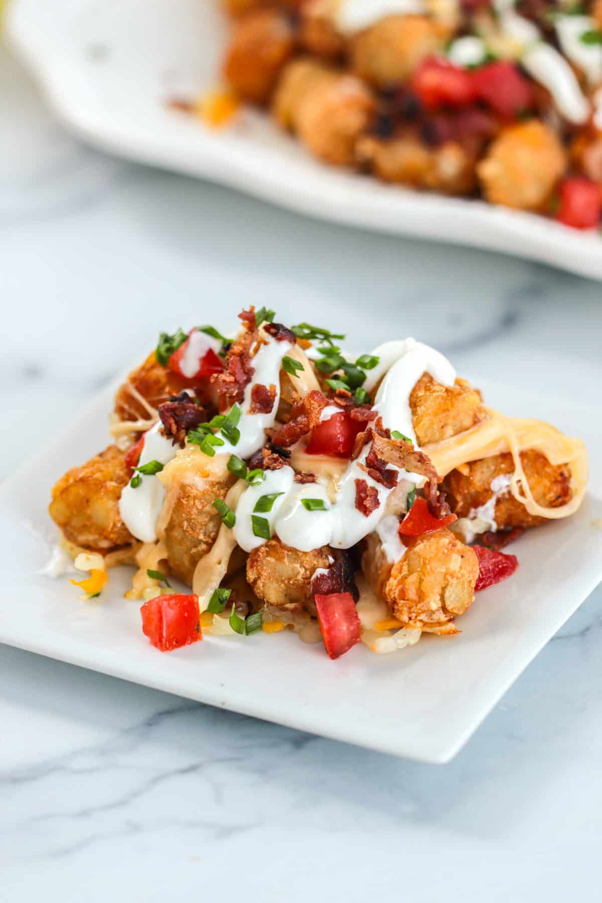 Tachos on a plate with sour cream, bacon and tomatoes.