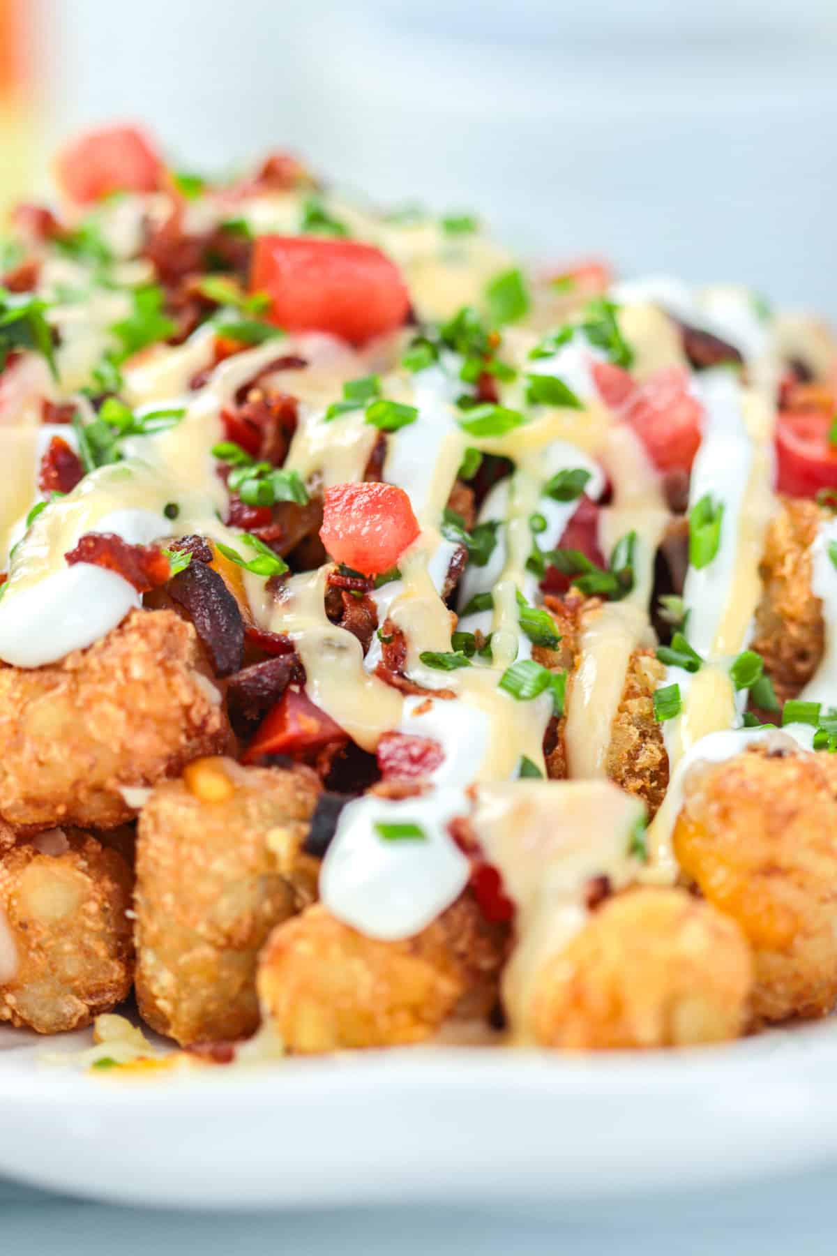 Loaded nachos with sour cream and cheese and tomaotes on a plate.