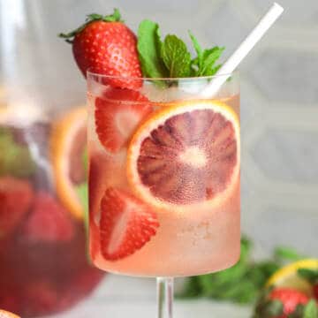 Rose sangria with fruit and a straw.