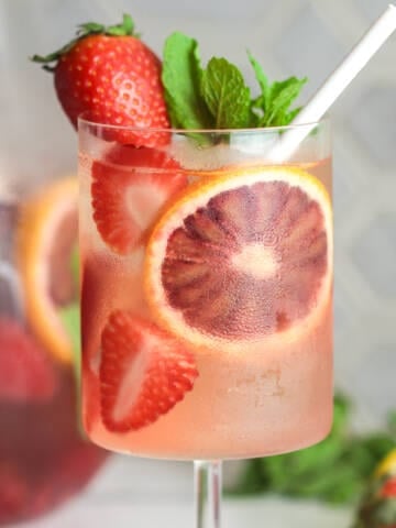 Rose sangria with fruit and a straw.