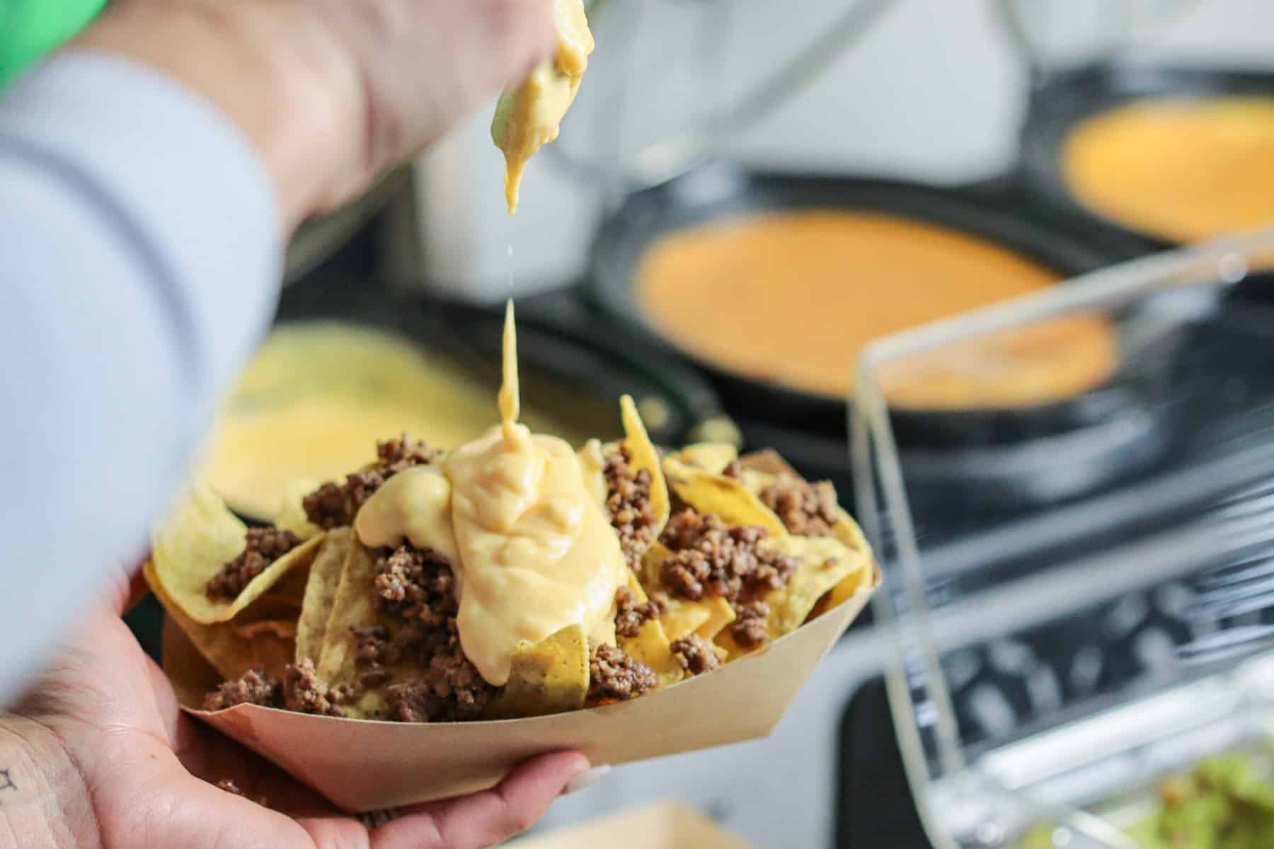 Pouring cheese sauce over nachos.