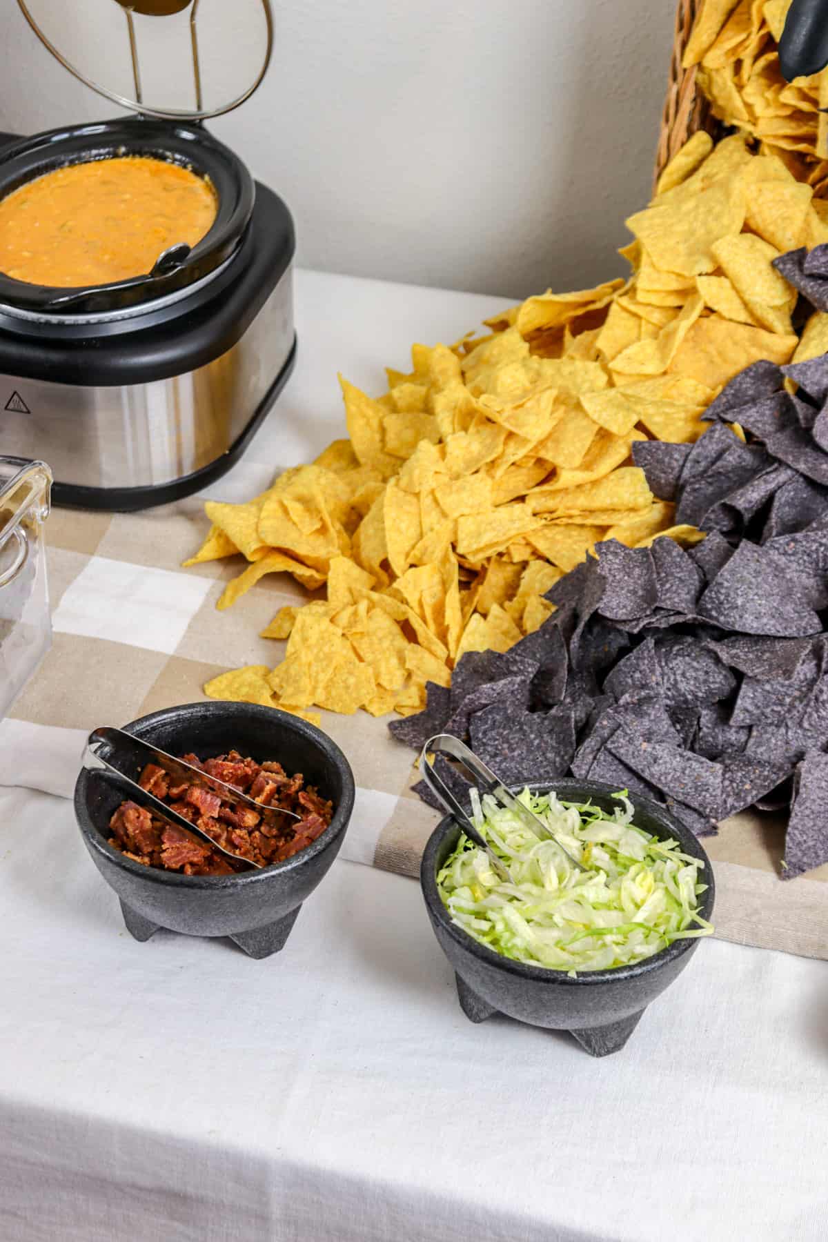 Tortilla chips cascading out of basket onto table for nacho bar.