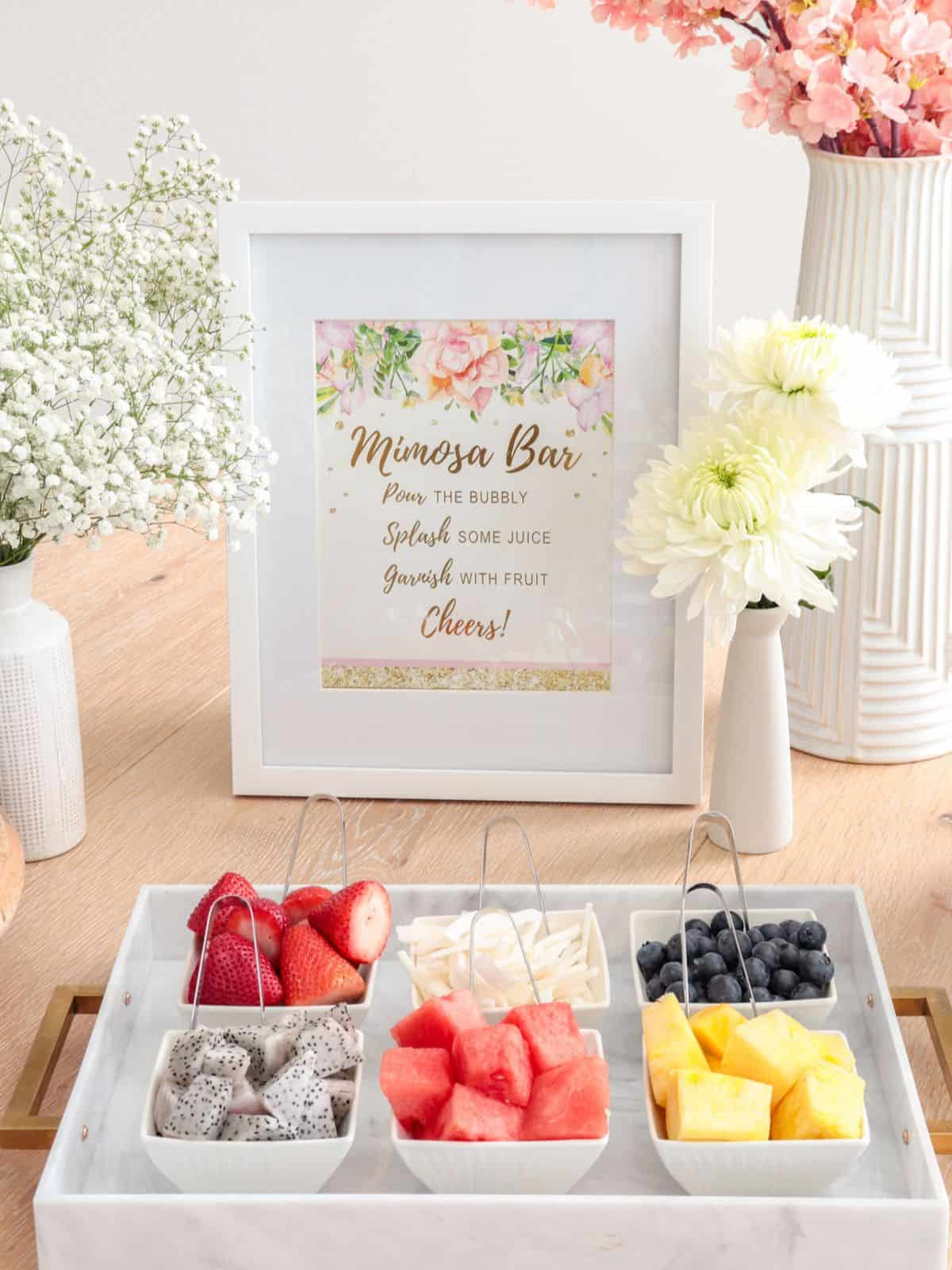 A mimosa bar set up with fruit and a sign.