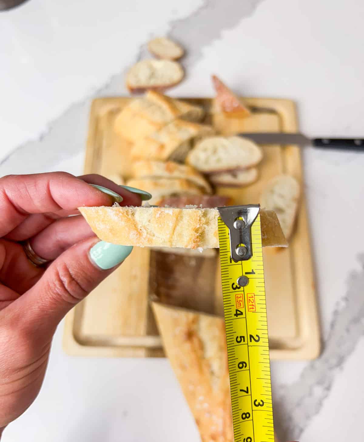 Showing how thick your crostini should be with a measuring tape.