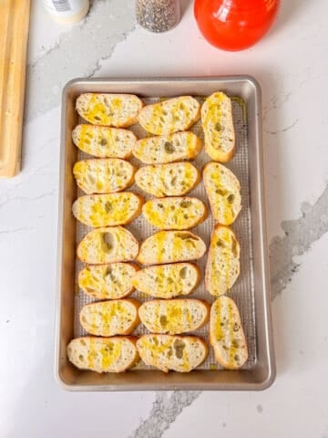 Crostini with olive oil in a baking sheet.