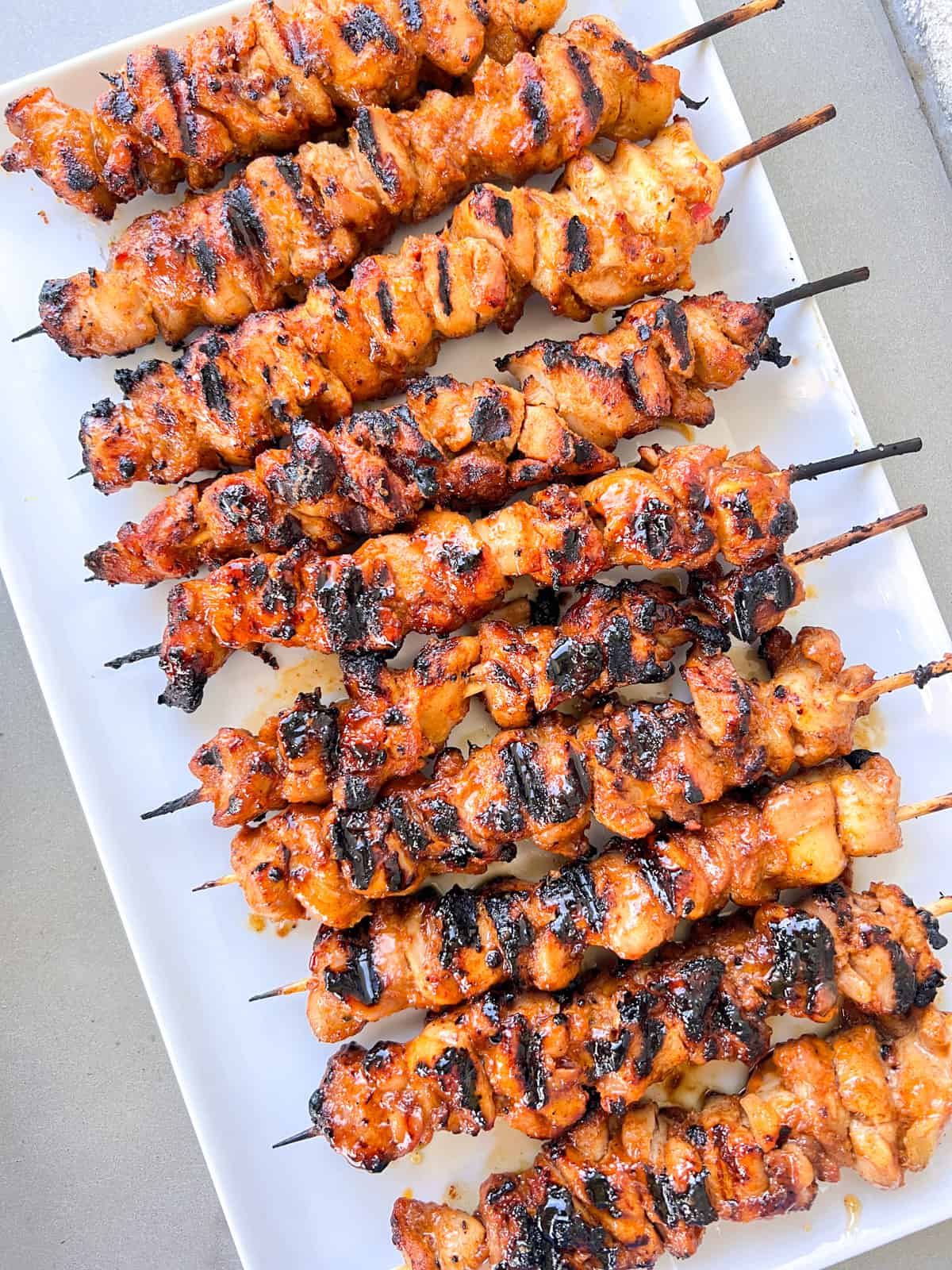 Grilled chicken skewers on white plate.