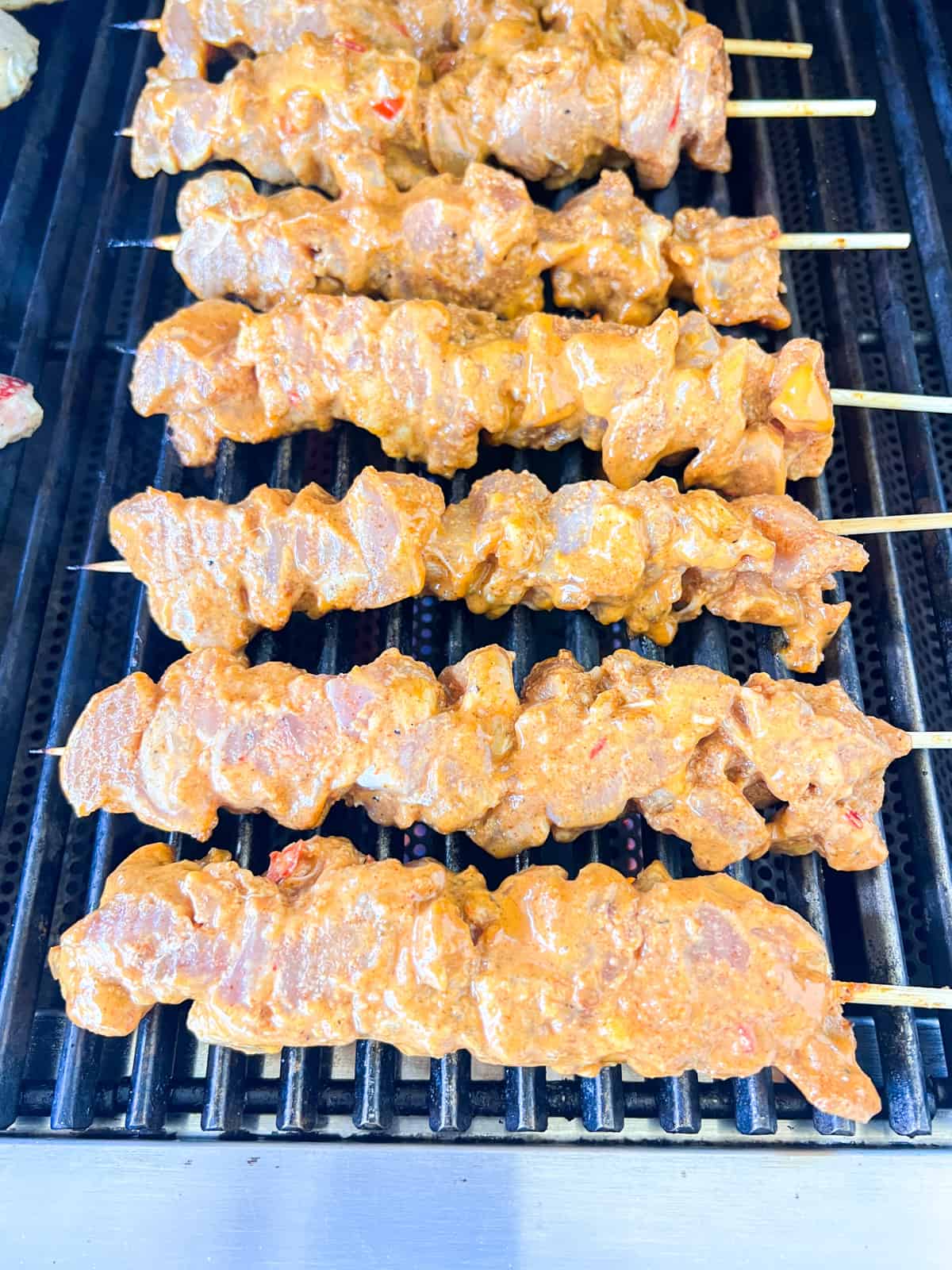 Chicken skewers on grill cooking.