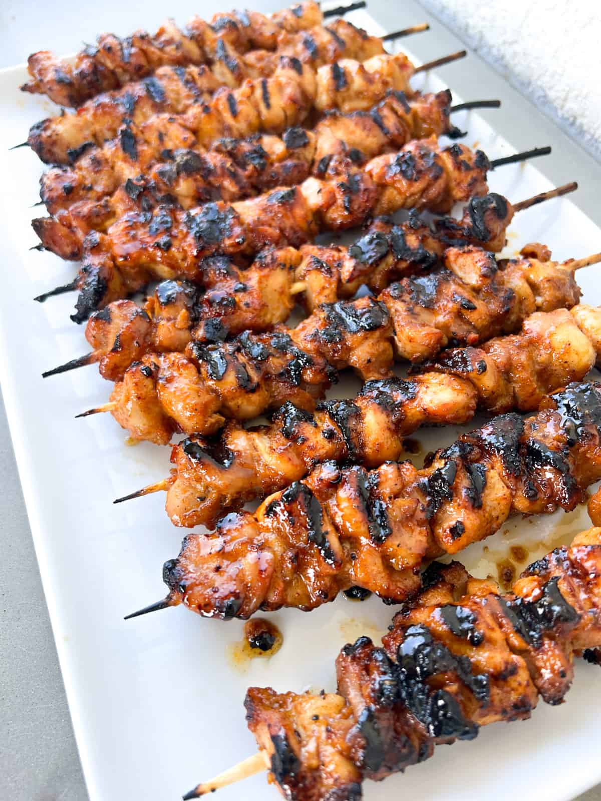 Grilled chicken thigh kabobs on skewers ona plate.