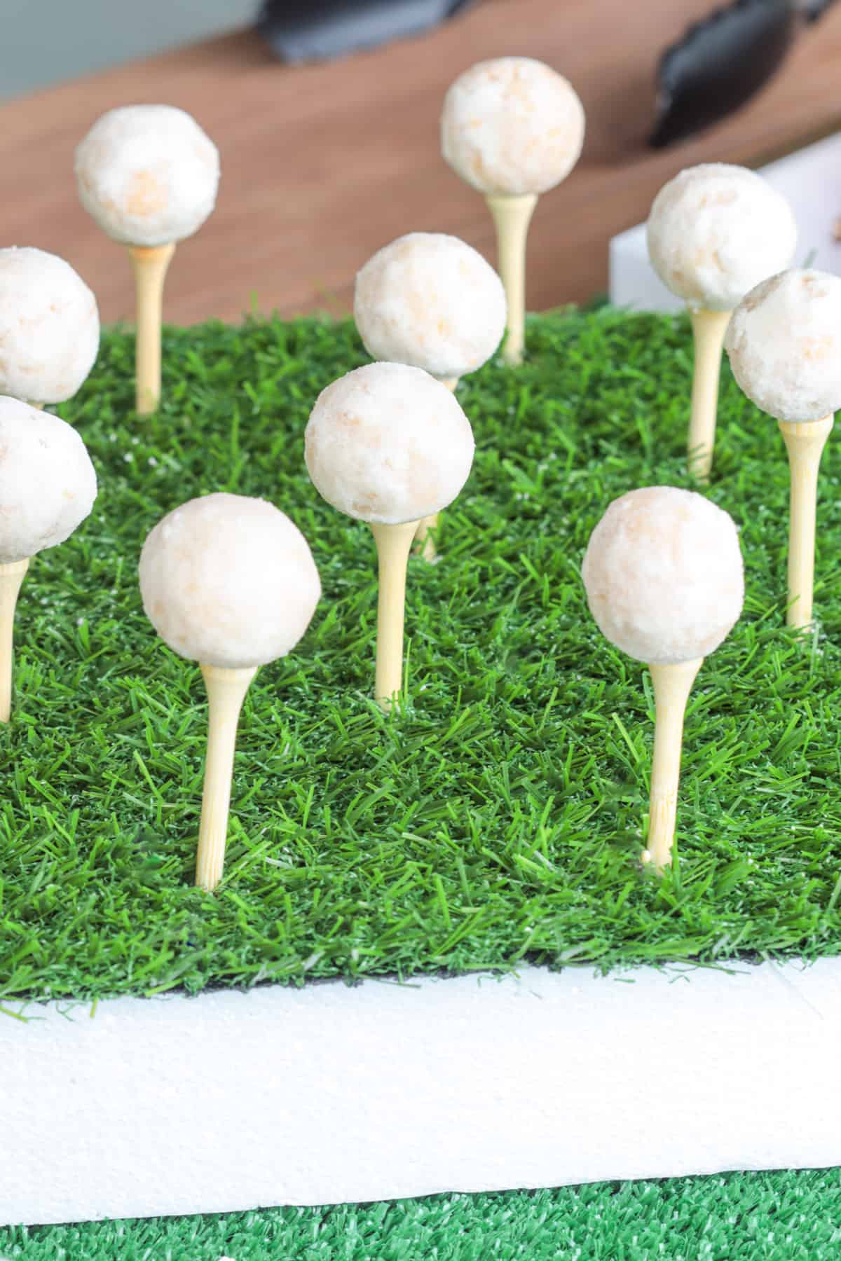 Golf tees in turf with donut holes on top.