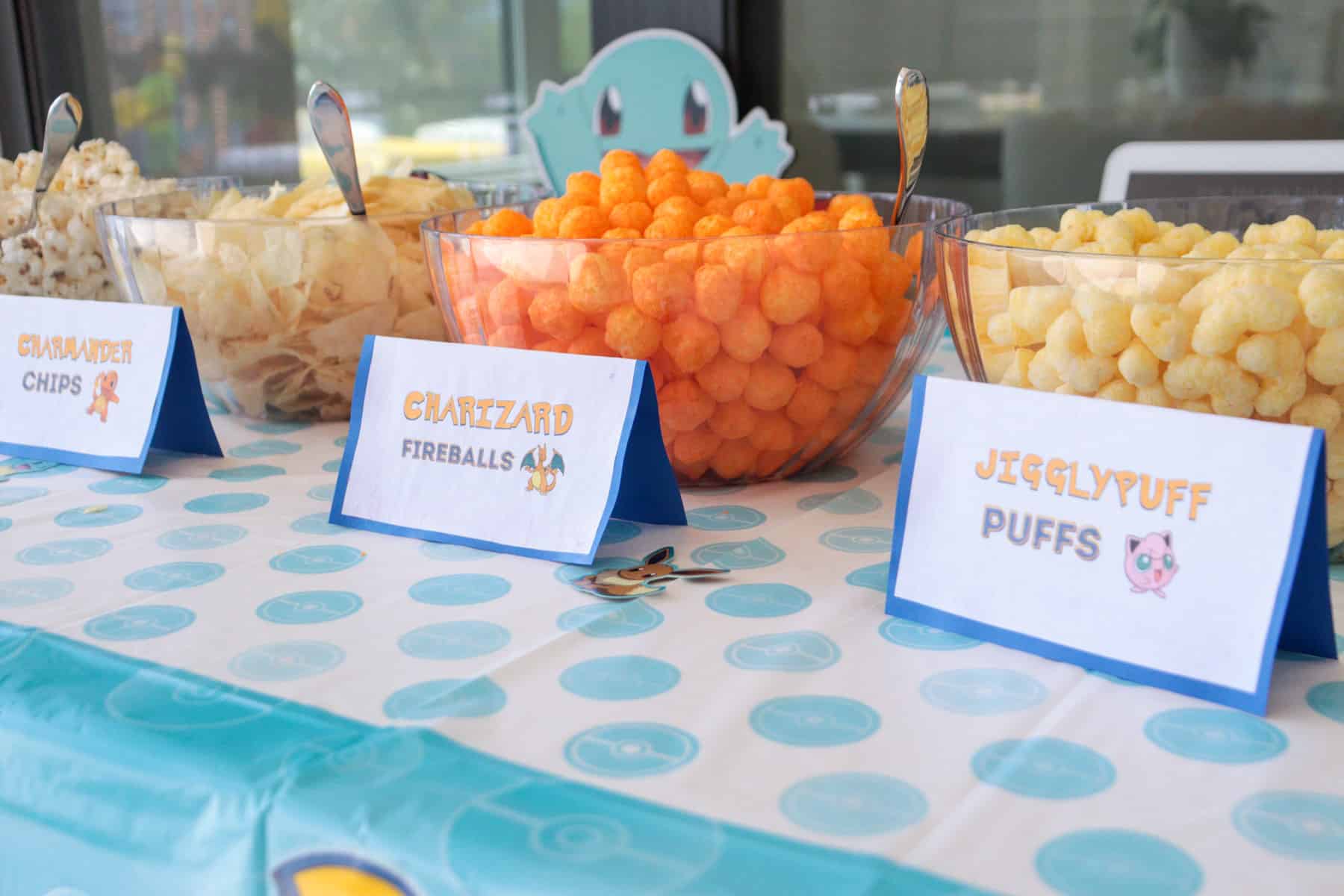 Snack table with food cards and bowls with snacks for party.