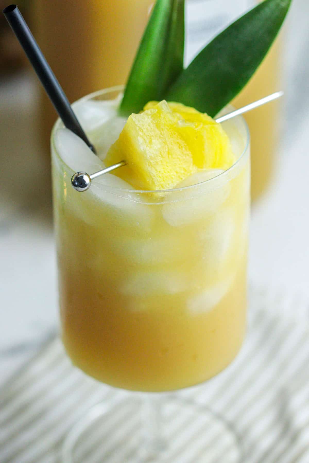 Pineapple coconut drink in a glass with straw.