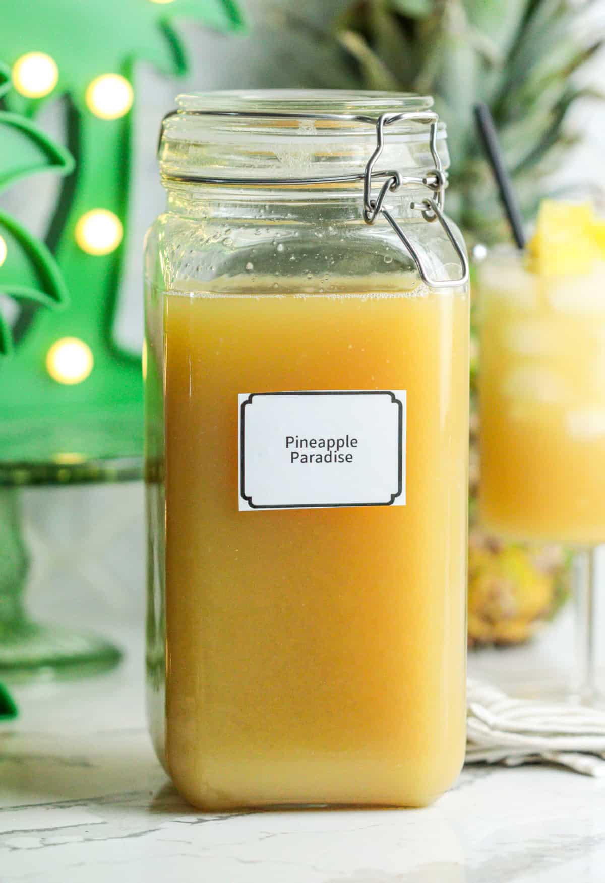 Batched pineapple cocktail in glass container.