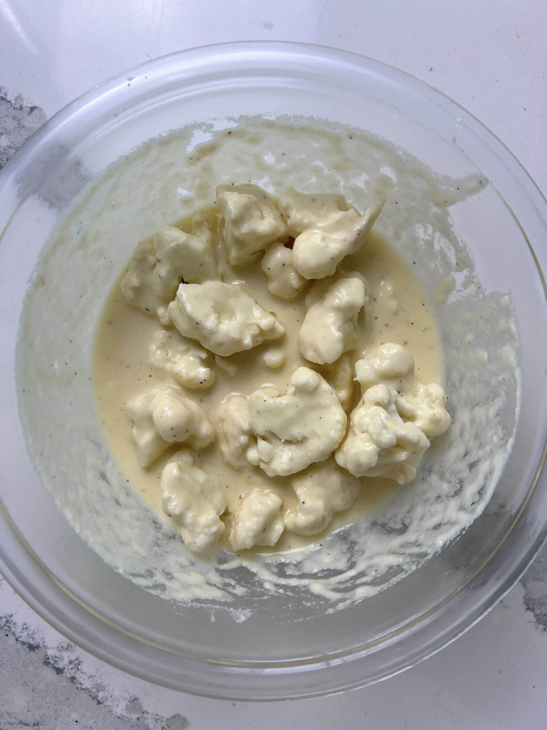 Cauliflower florets in batter in a bowl.