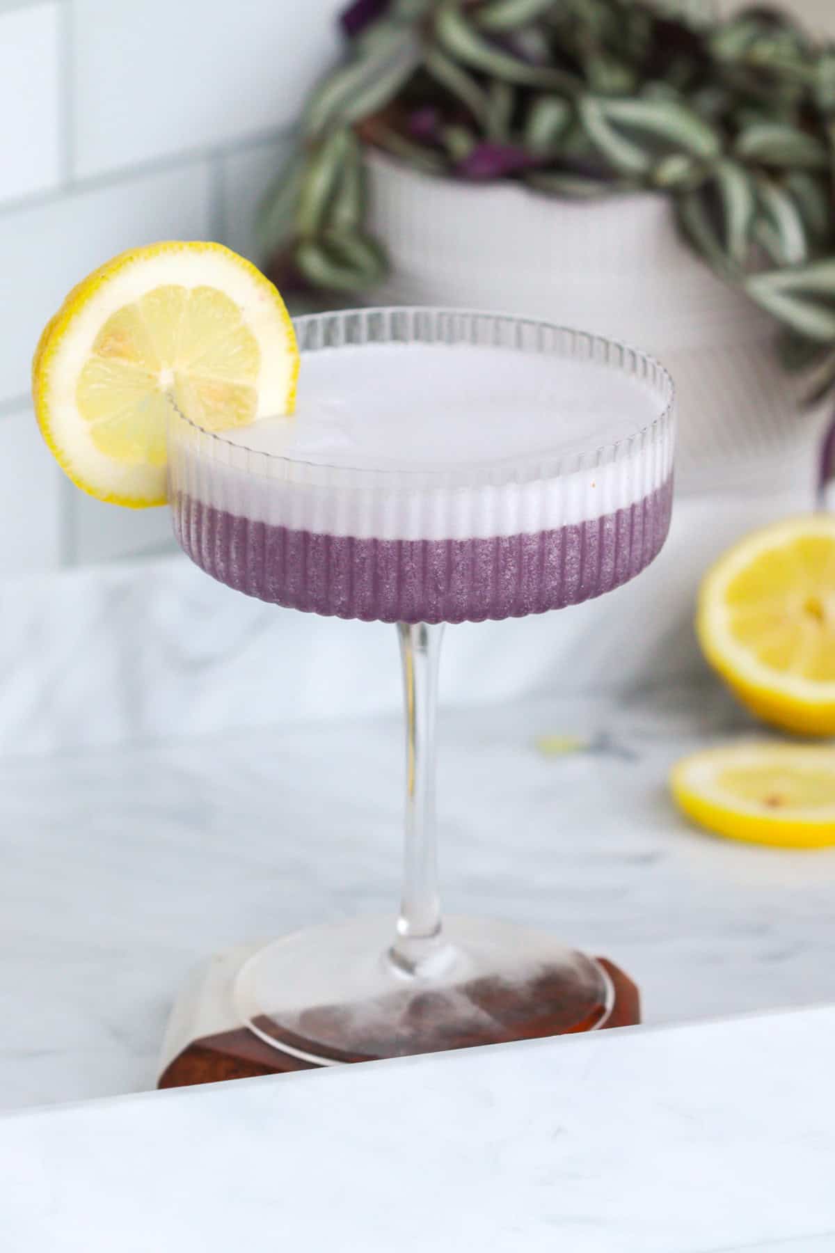 Violet lady cocktail with creme de violette and lemon wheel.