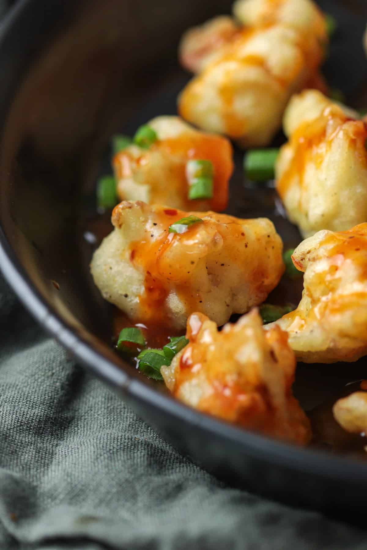 Fried sweet spicy chili cauliflower on a black plate.