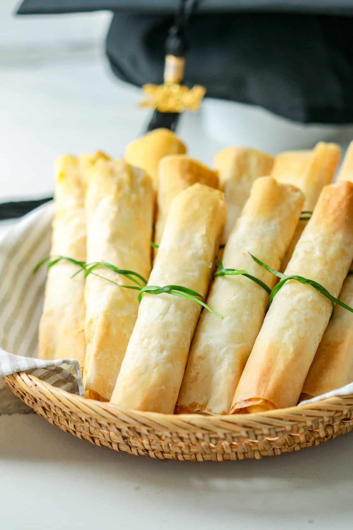 Phyllo dough diplomas rolled and stuffed with feta cheese in a basket.