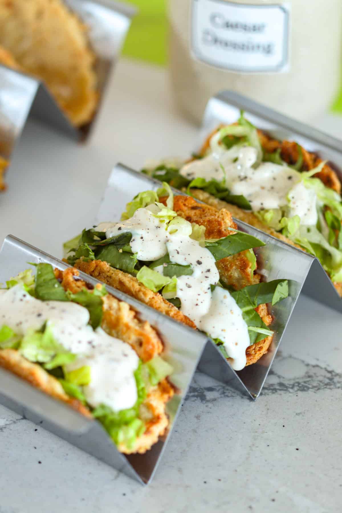 Caesar salad tacos in a taco holder on table.