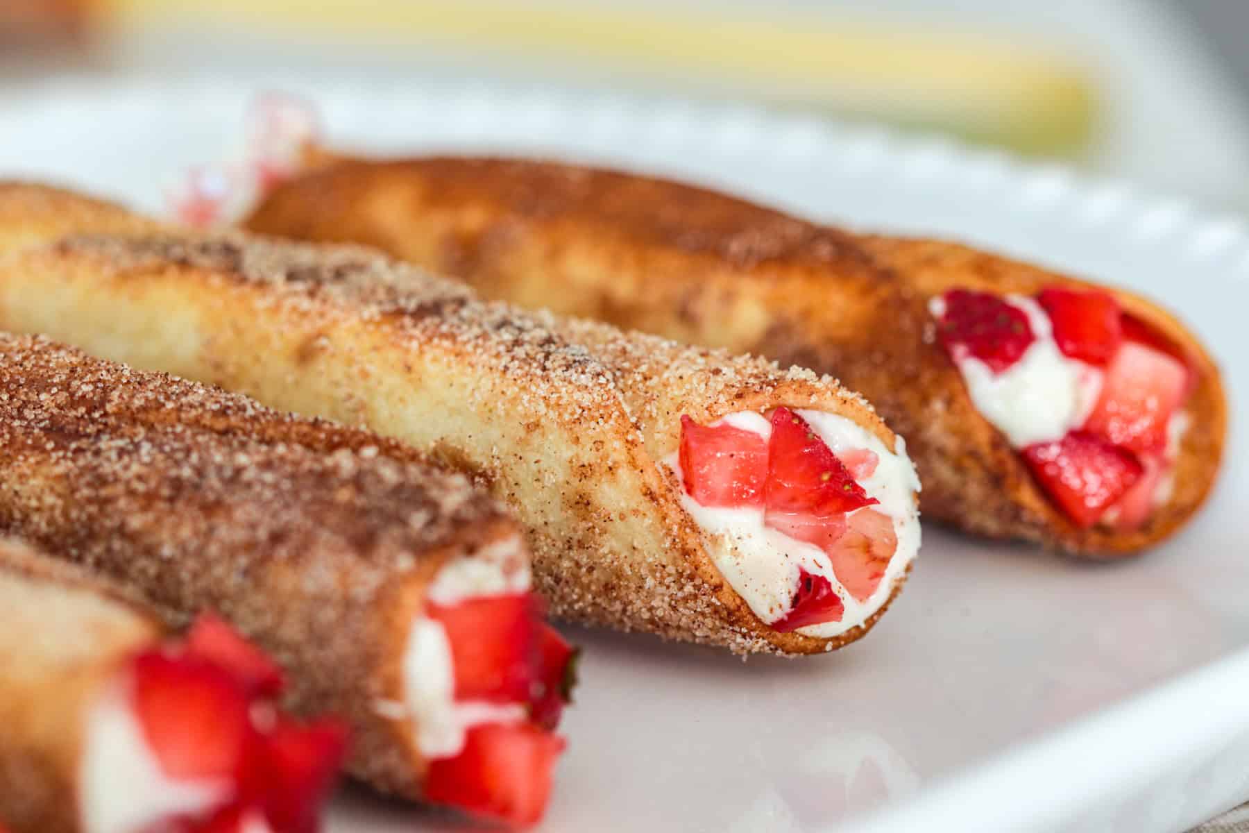 Strawberries on the end of a cheesecake cannoli.