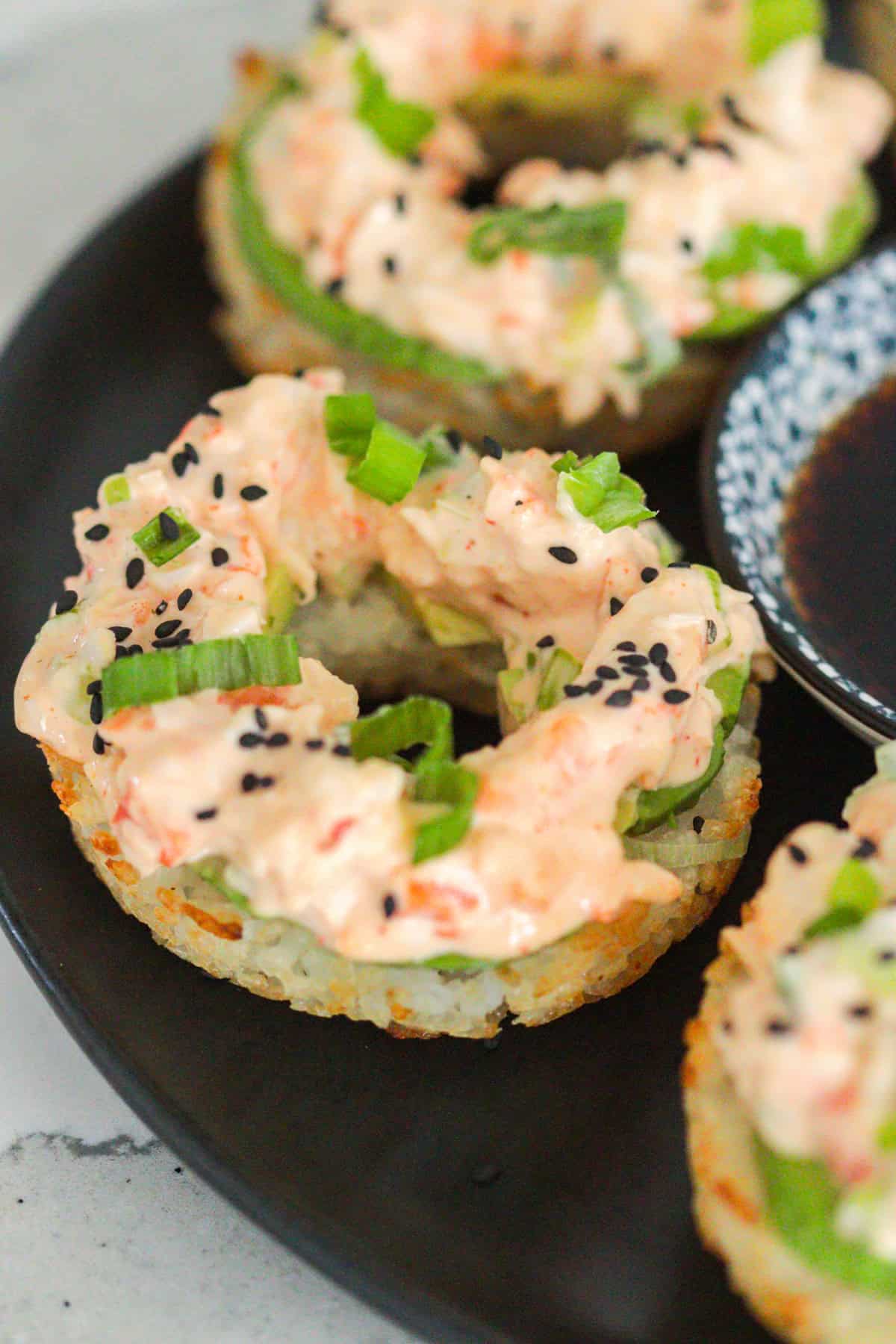 Sushi donuts on plate with sesame seeds and scallions.