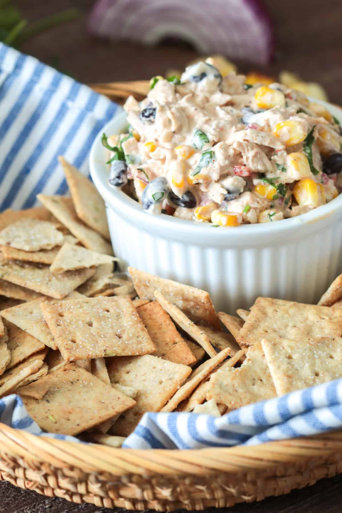 Chicken salad with beans and corn in a bowl with crackers.