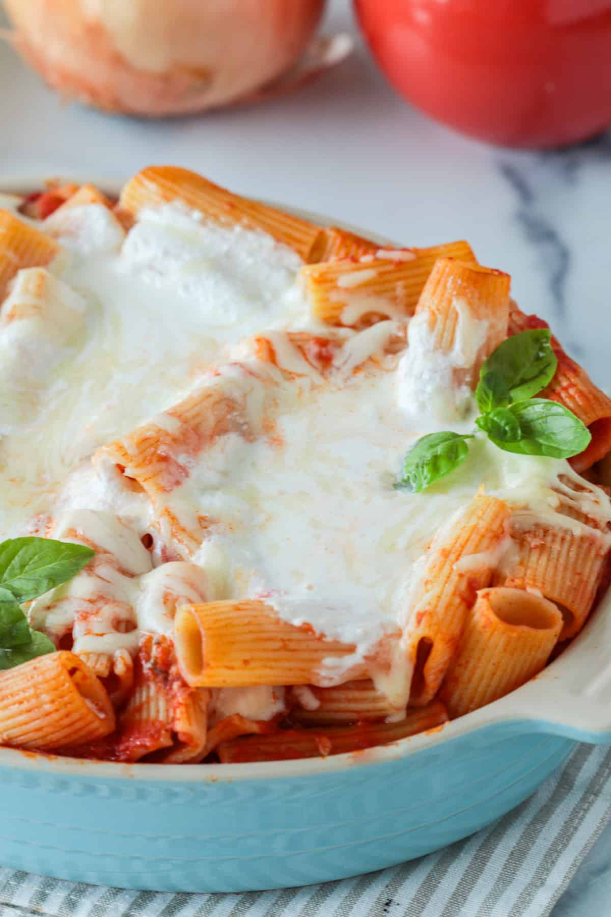 Cheesy baked ziti in a baking dish with fresh basil.