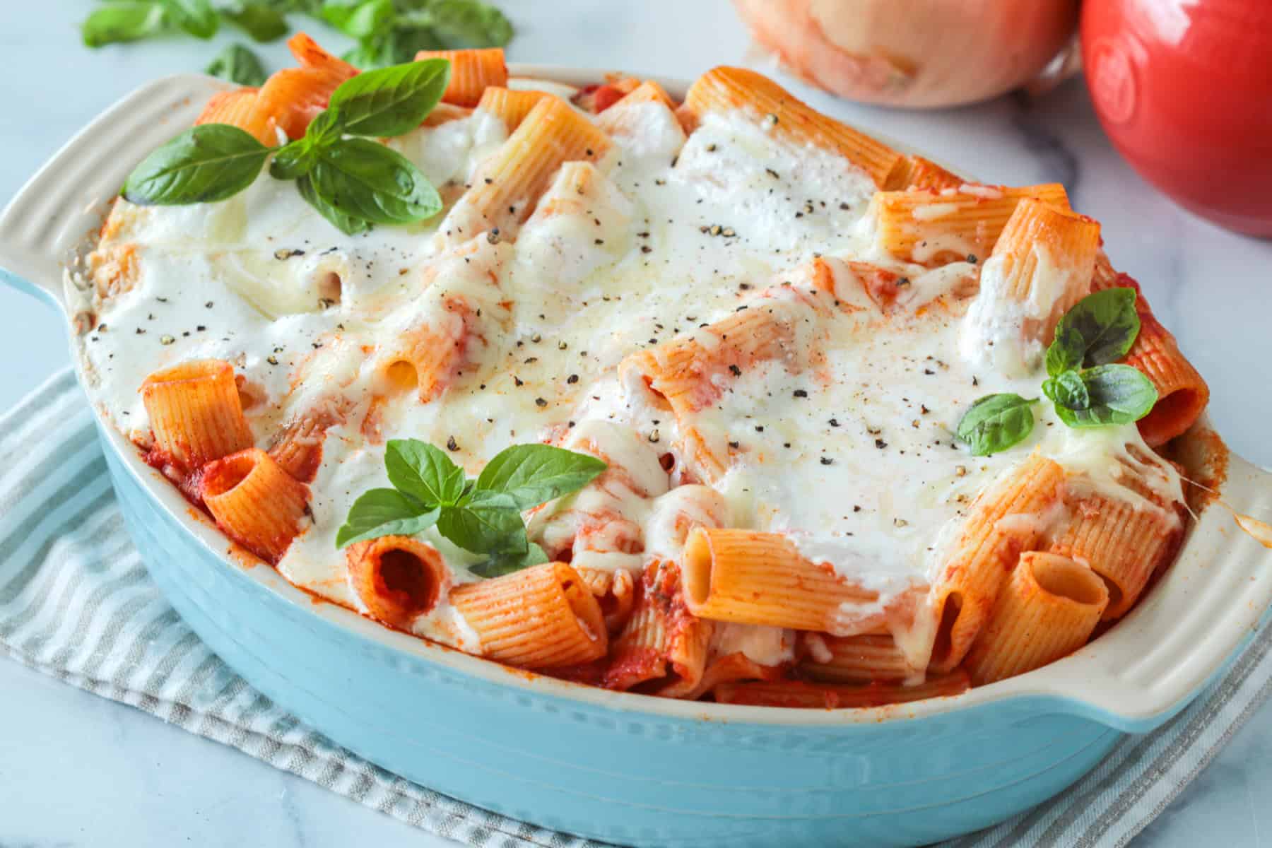 Baked ziti in a casserole dish with lots of cheese on top.