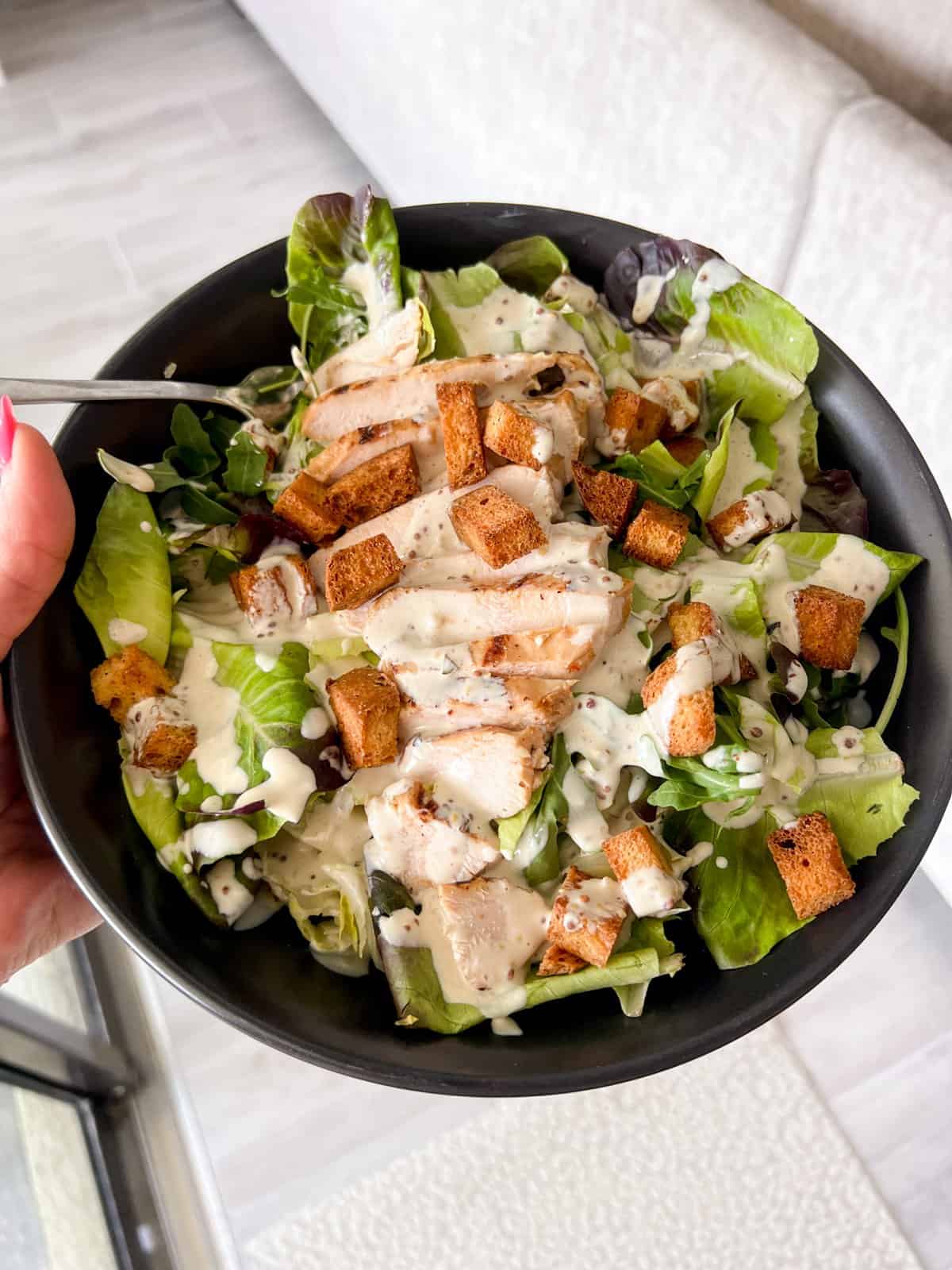 Caesar salad in a bowl with grilled chicken.