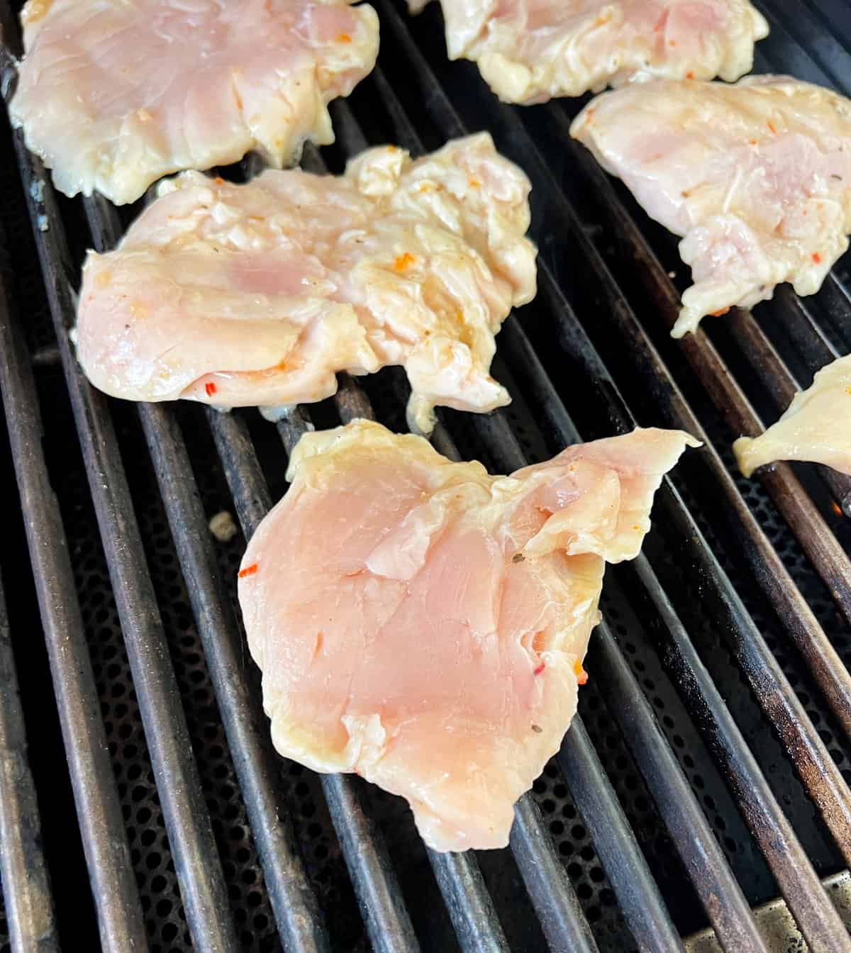 Raw chicken breasts on the grill.