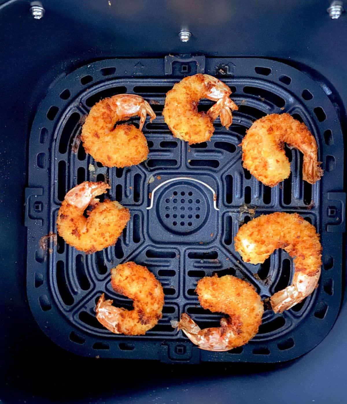 Fried shrimp in air fryer basket.