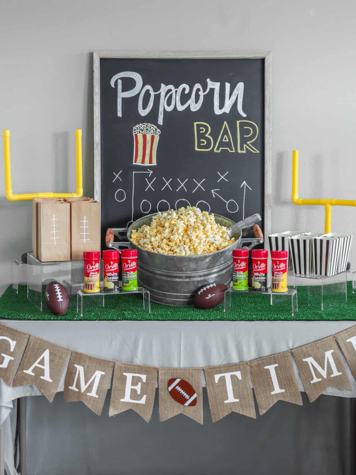 Popcorn bar set up woth seasonings and football decor.