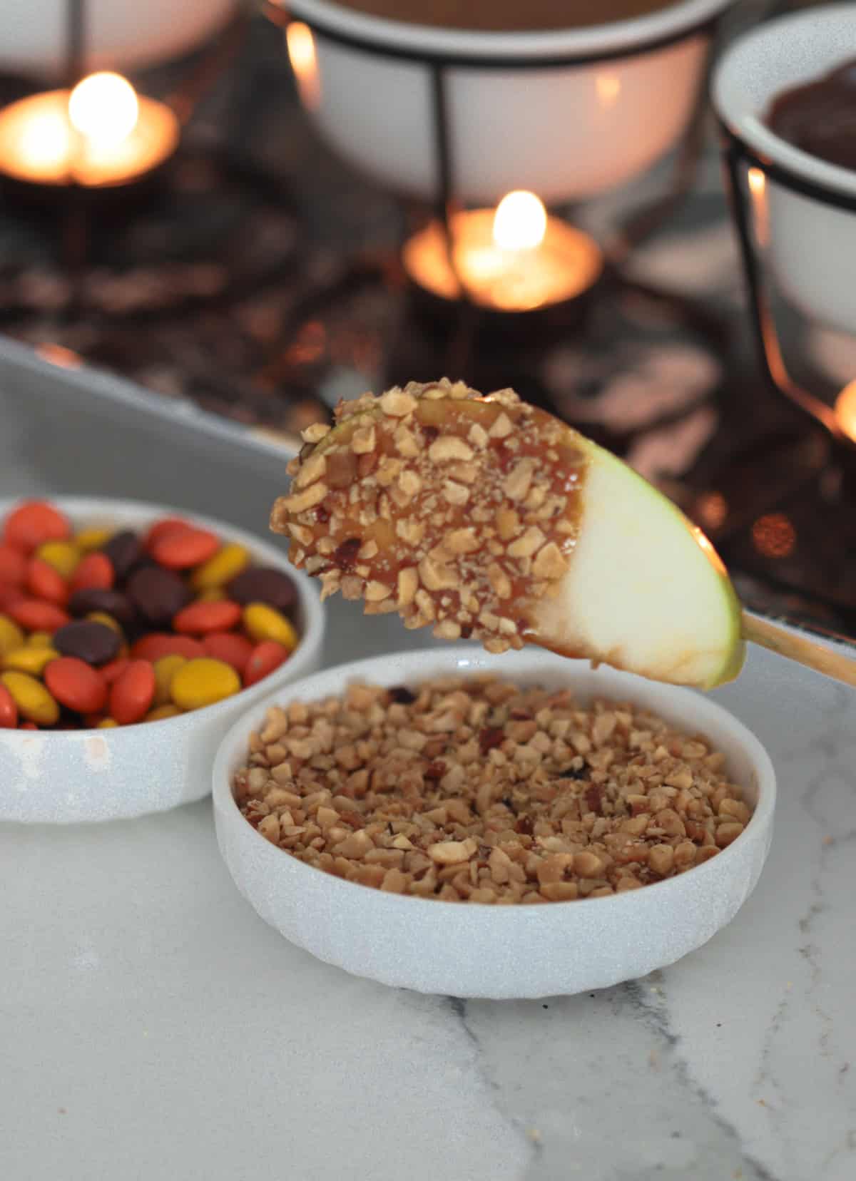 Dipping caramel apple into nuts.