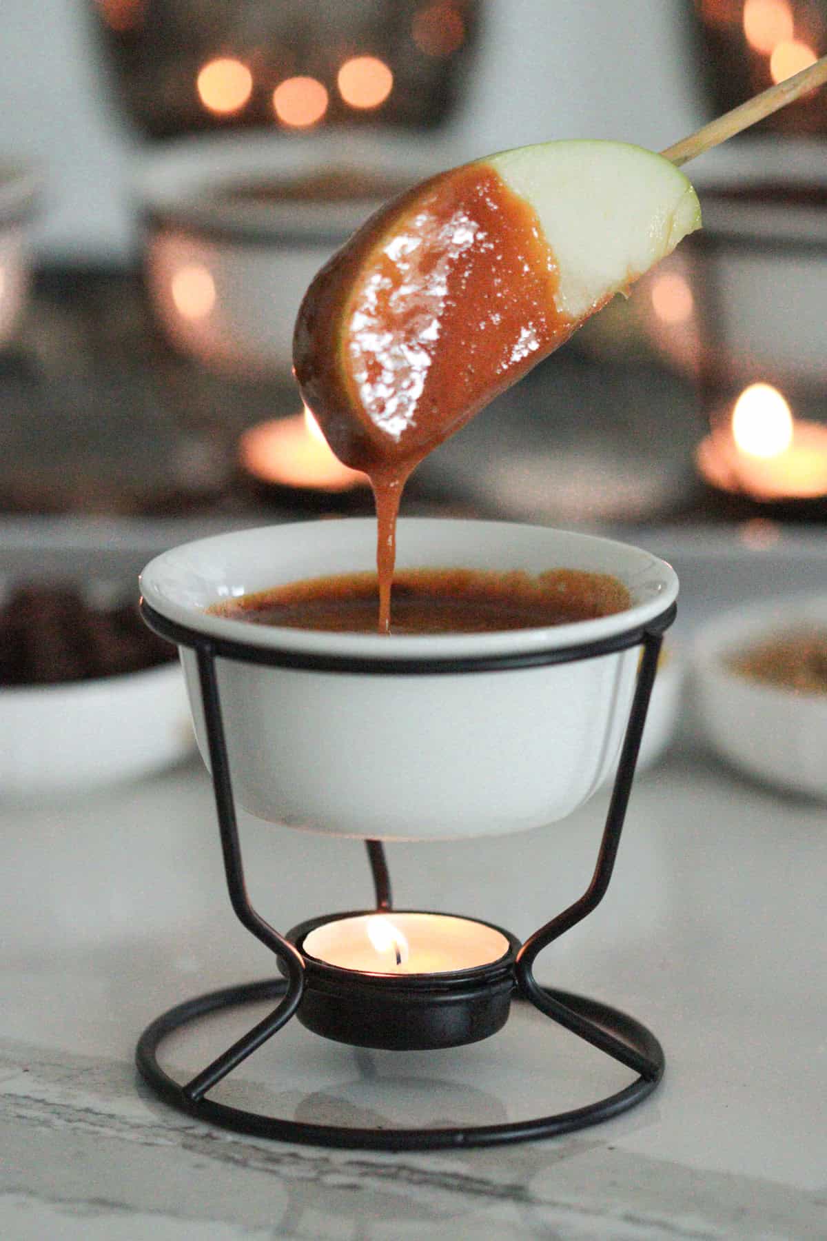 Apple being dipped into caramel sauce.