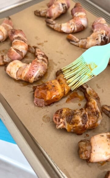 Shrimp wrapped with bacon brushed with mixture.