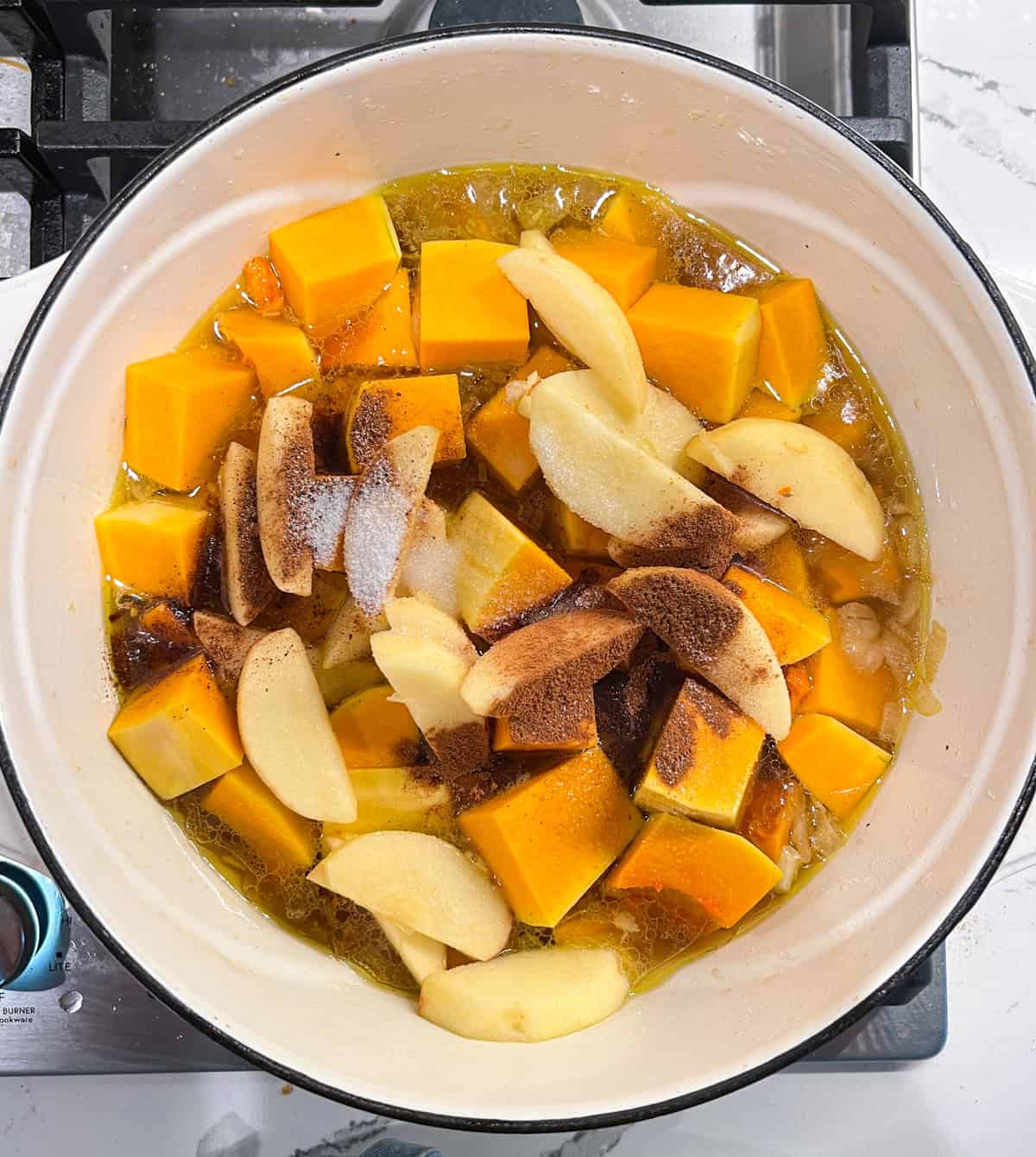 Cut up butternut squash and apples in a pot with spices and stock.