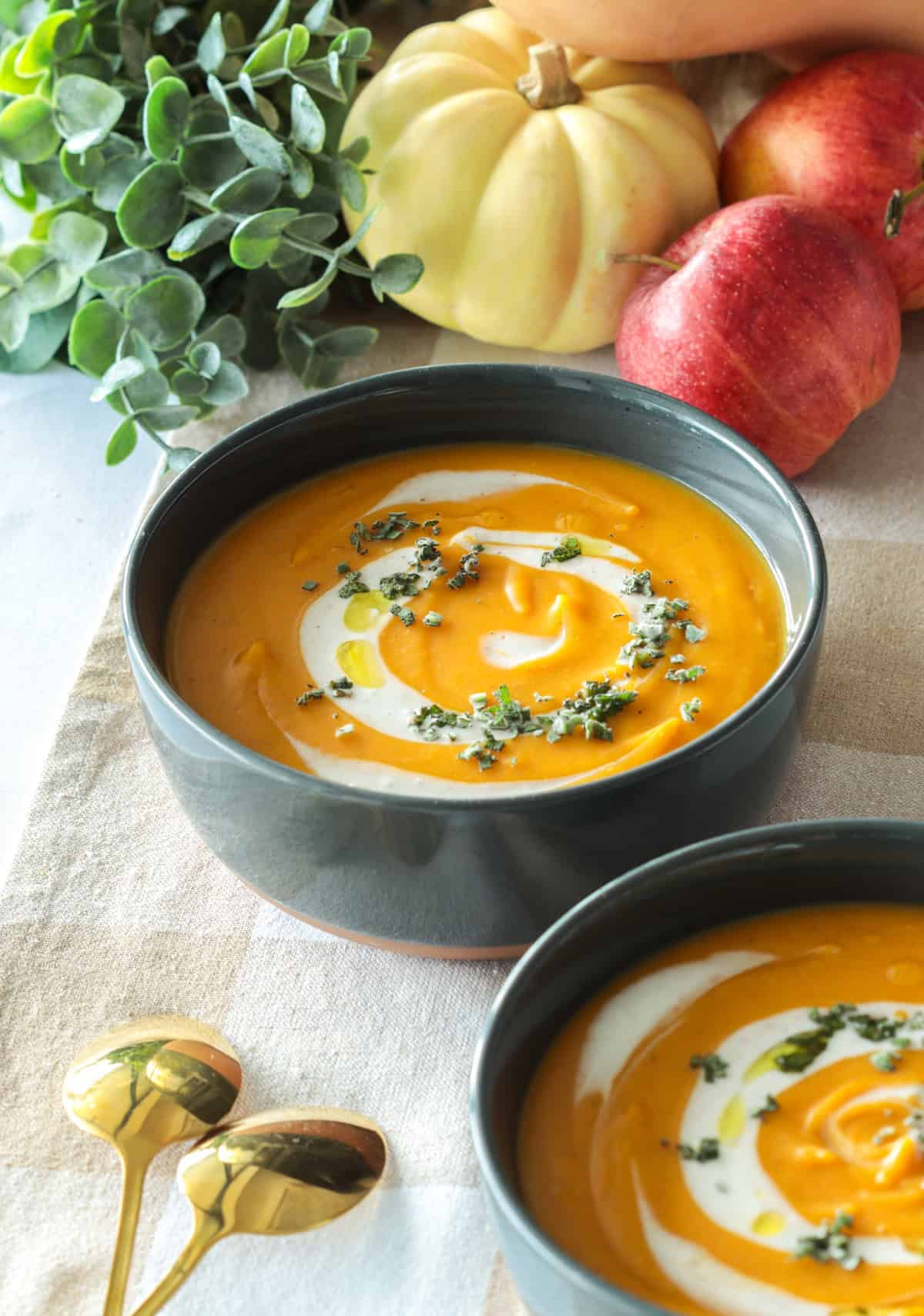 Butternut squash soup in bowl with sage garnish.