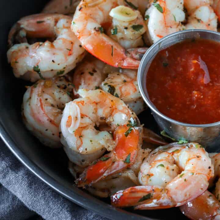 Garlic cocktail shrimp in a bowl with cocktail sauce.