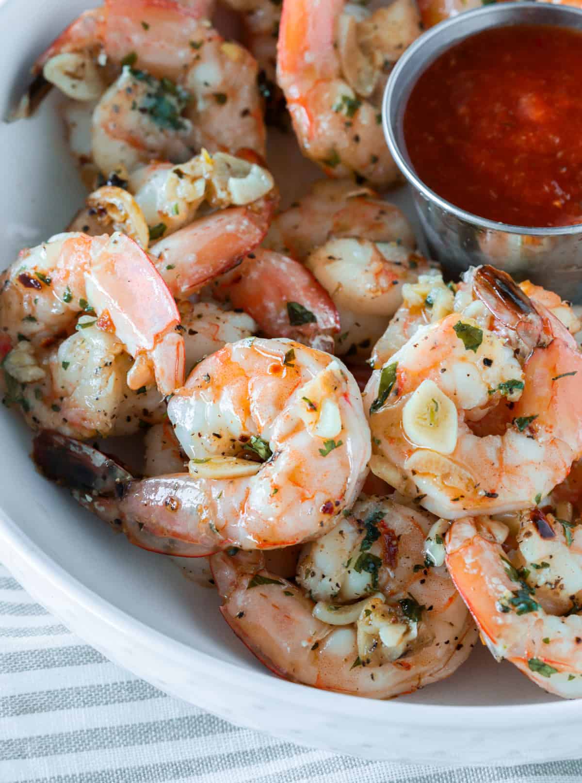 Roasted garlic shrimp cocktail in a bowl with garlic and tarter sauce.