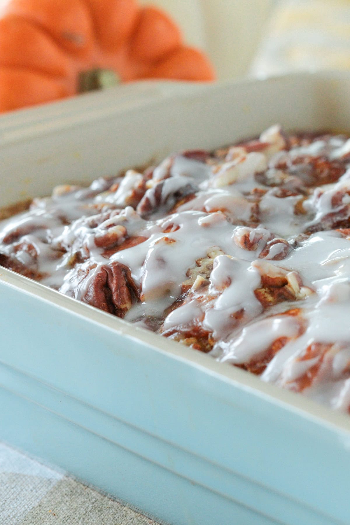 Pumpkin cinnamon bun casserole with icing over top in casserole dish.