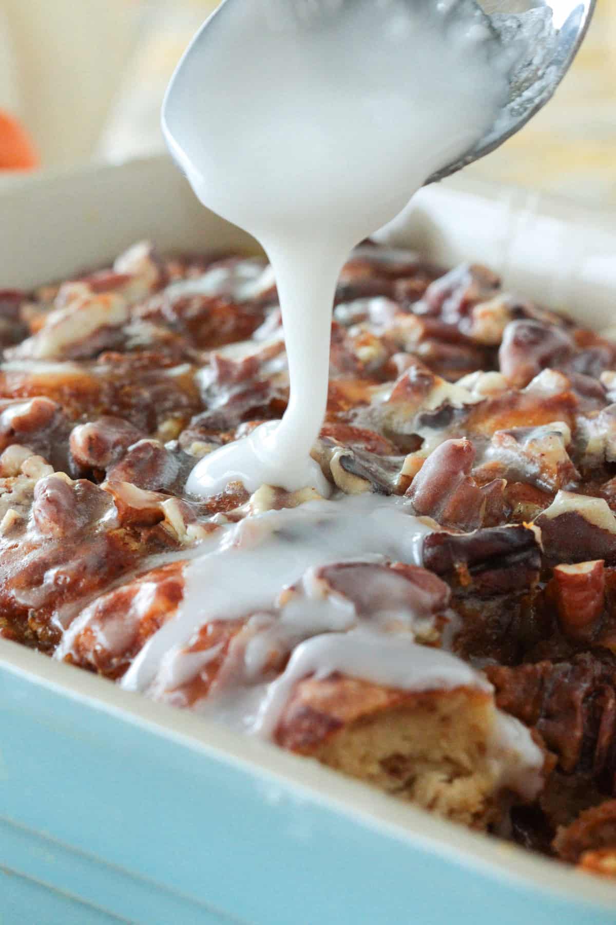 Pumpkin cinnamon roll french toast casserole with icing being drizzled over top.