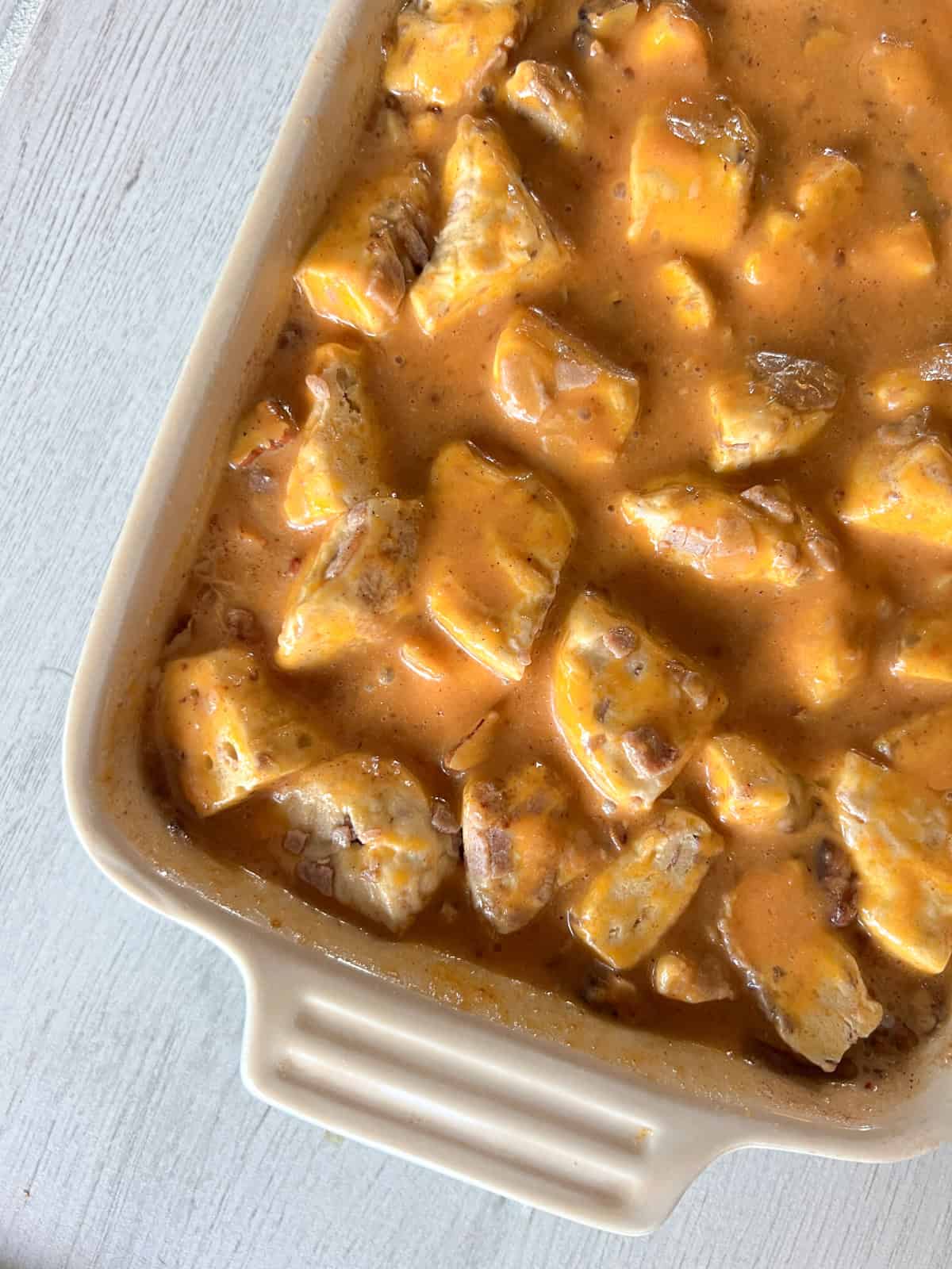 Pumpkin cinnamon roll casserole in a baking dish with eggs.