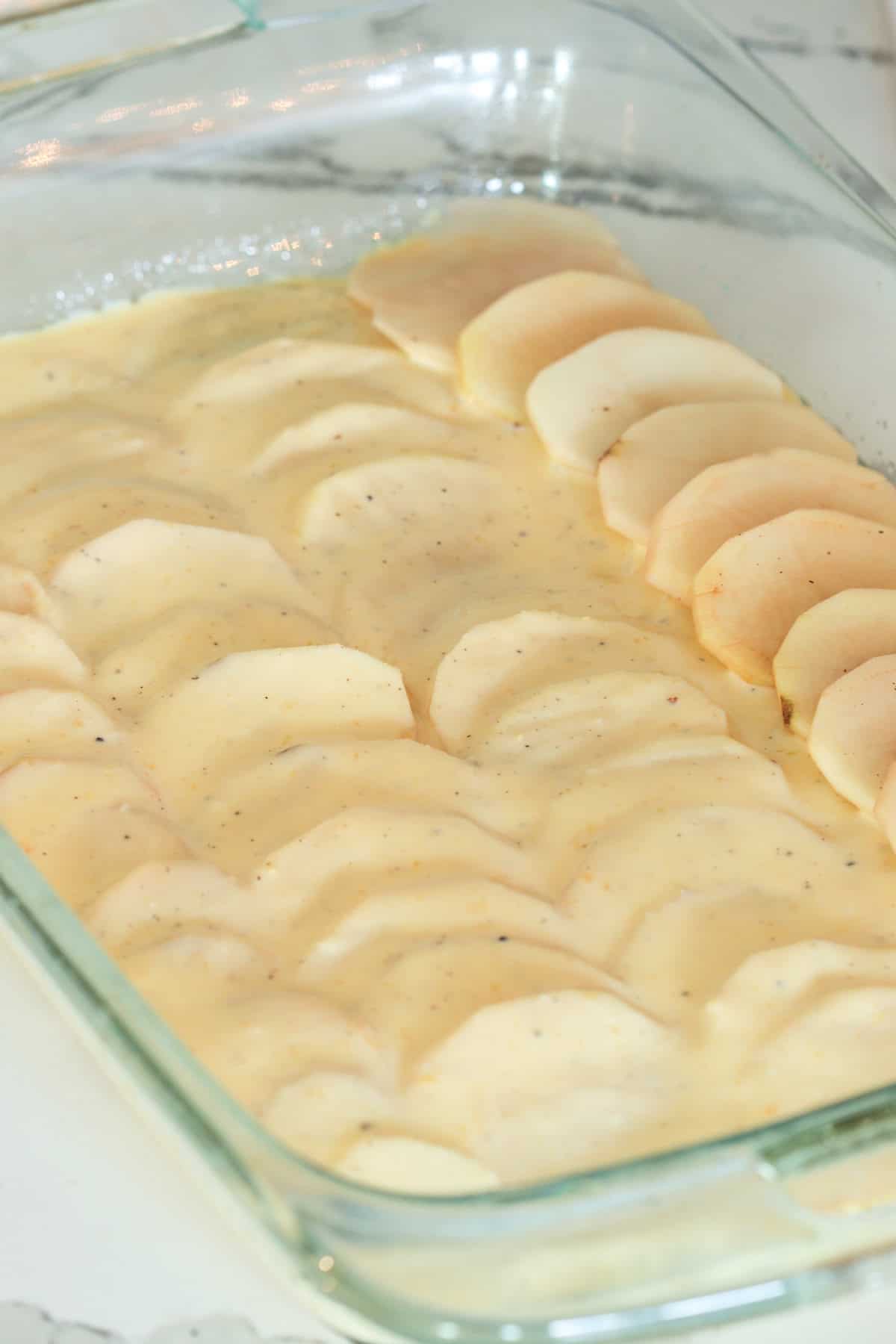 Layering the sliced potatoes with sauce.