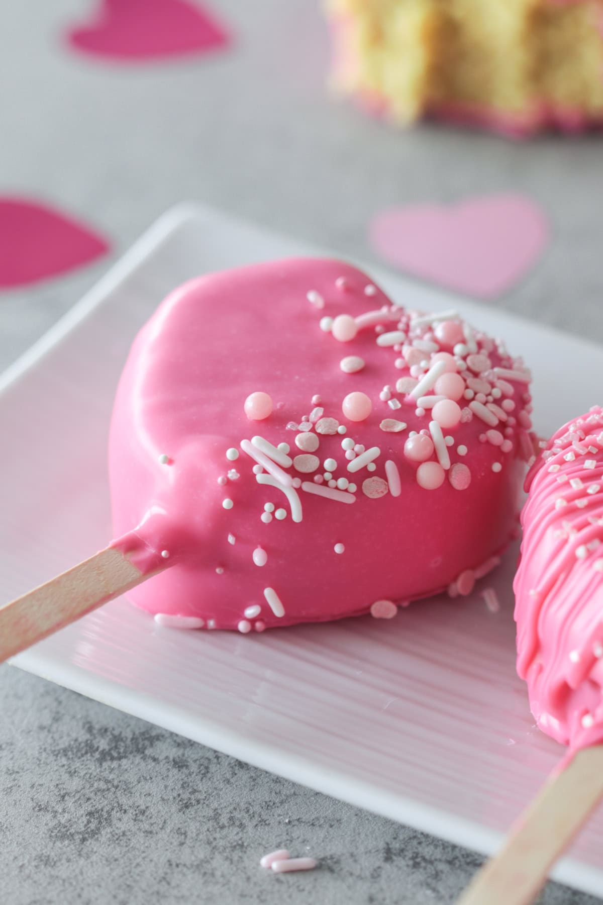 Pink heart cake pops on a plate.