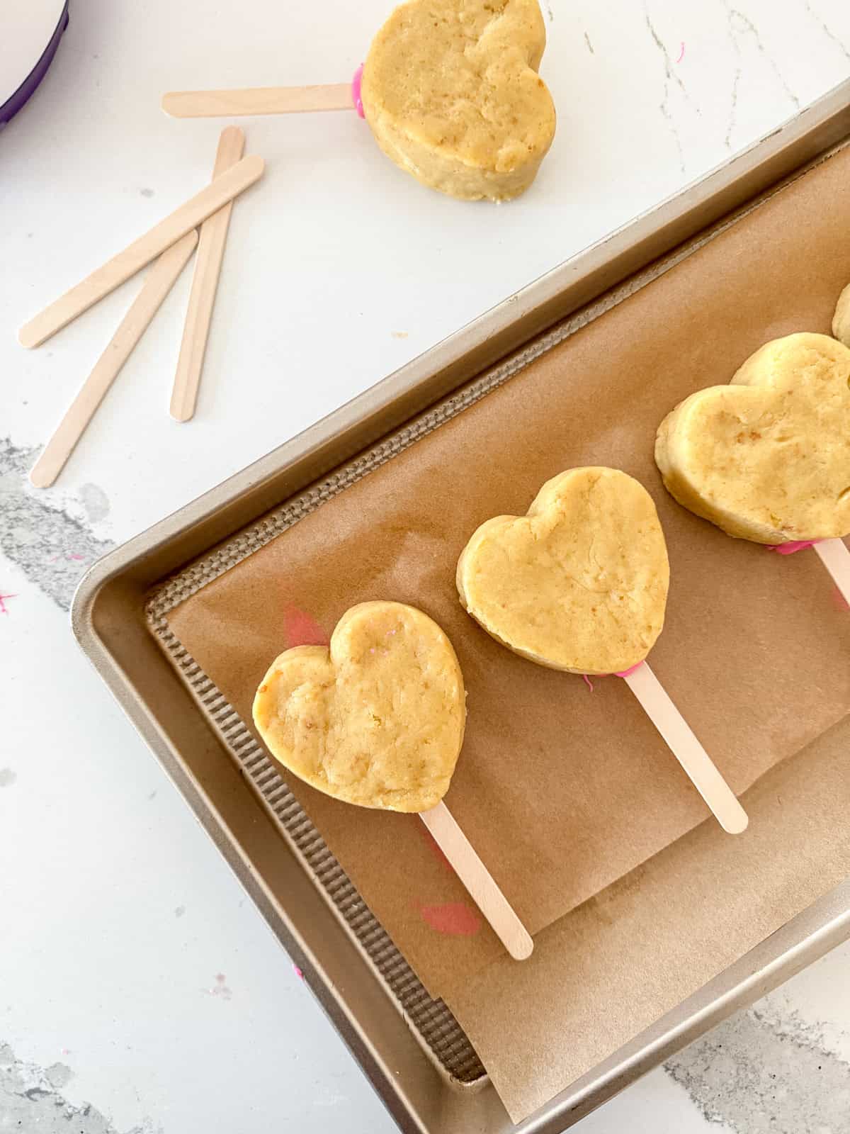 Heart cake pops on stick waiting to be dipped.