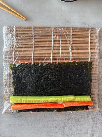 Bamboo mat with nori, rice and sushi filling.