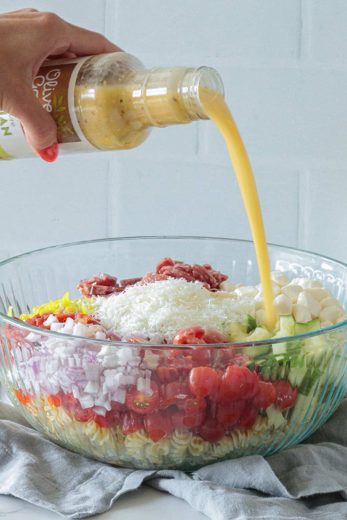 Pouring Italian dressing over top of salad.